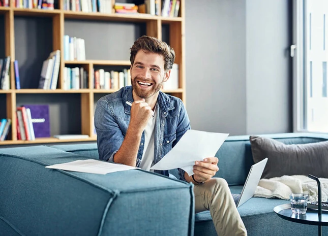 Ein Mann sitzt auf einem blauen Sofa mit Zettel und Stift