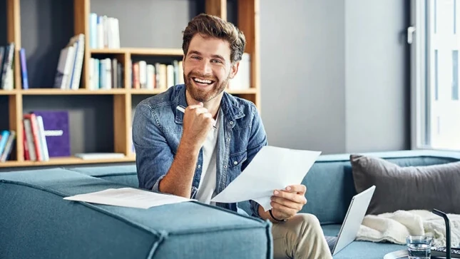 Ein Mann sitzt auf einem blauen Sofa mit Zettel und Stift