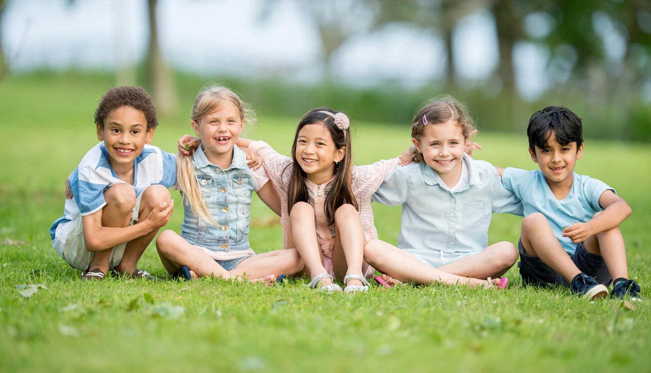 Fünf Kinder sitzen auf einer Wiese