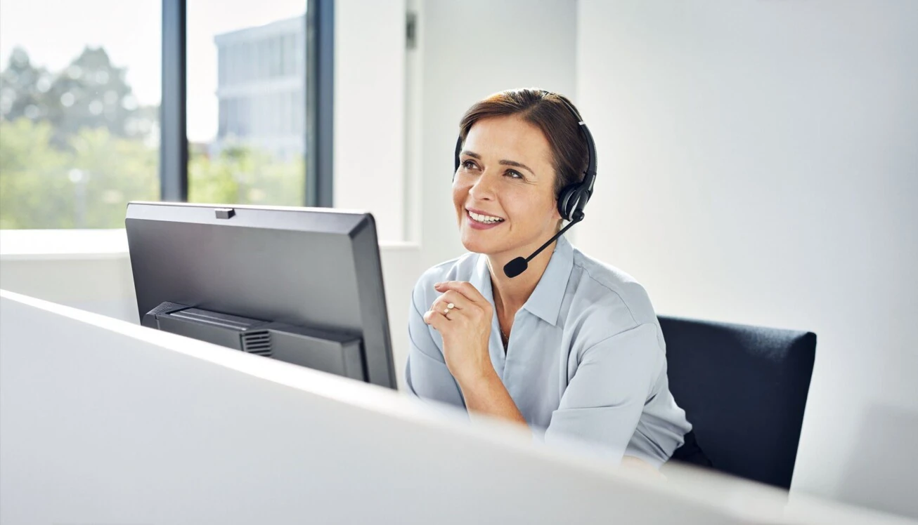 Frau mit Headset sitz an einem PC